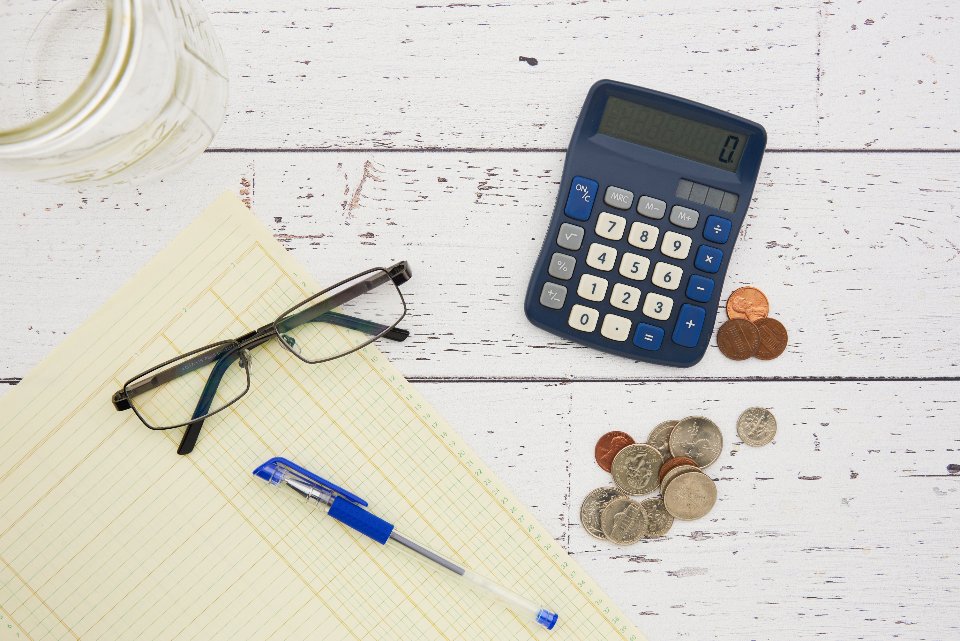Calculator, notepad and US coins used to compare car insurance deductibles and liability coverage limits